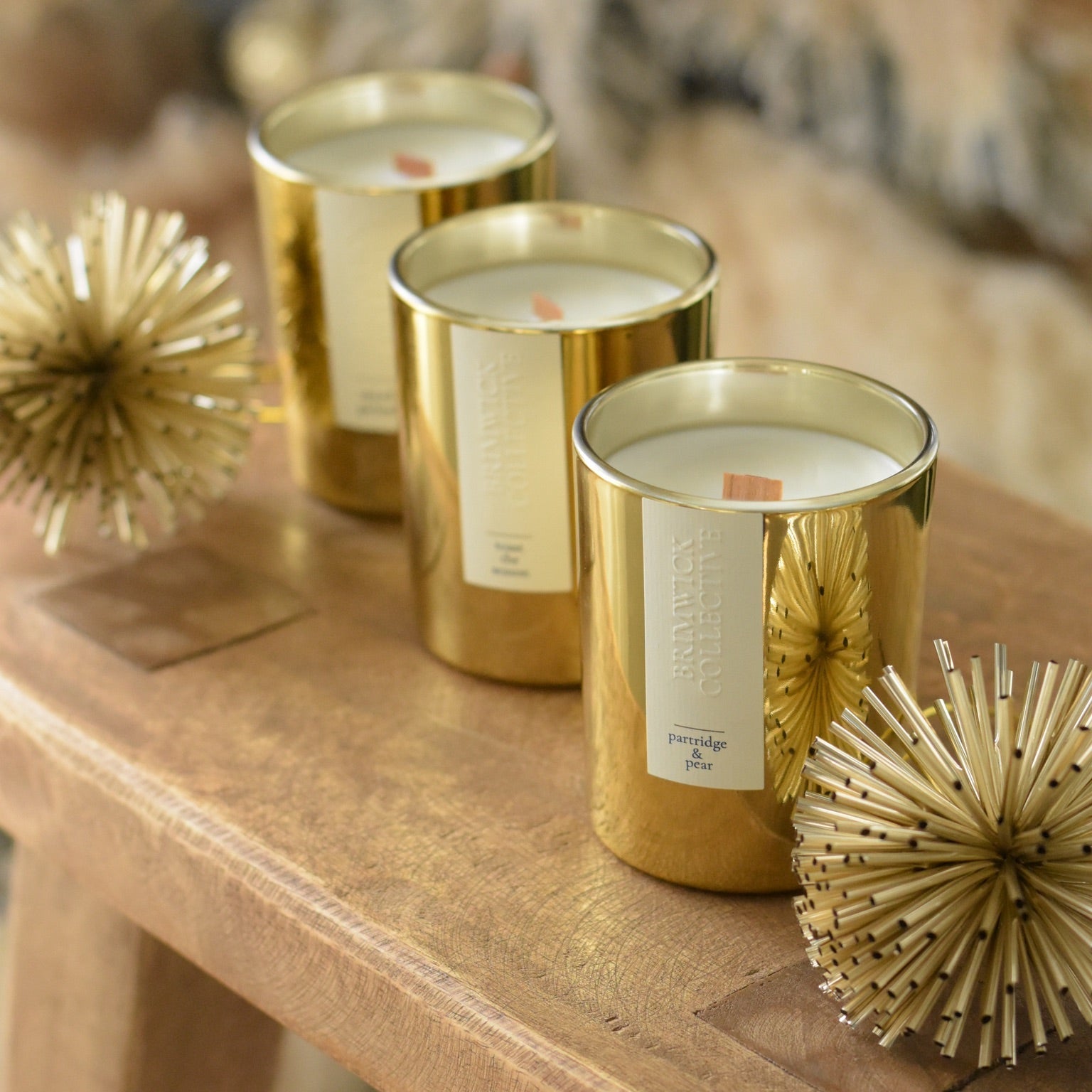 Three gold candles on a wooden surface with decorative elements.