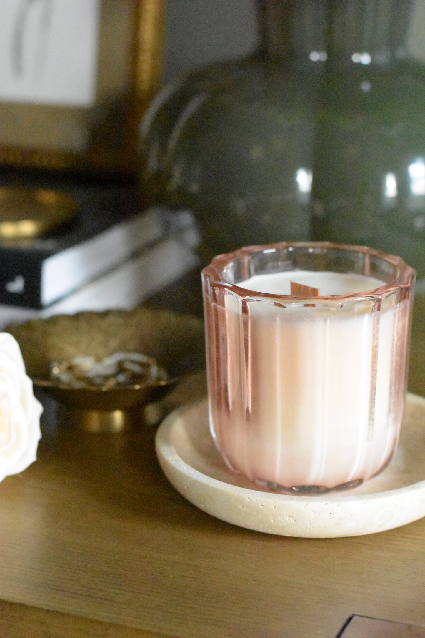 Pink glass candle on a white coaster with a blurred background